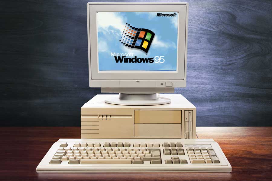 An old, bulky desktop computer has the Windows 95 logo on the screen.