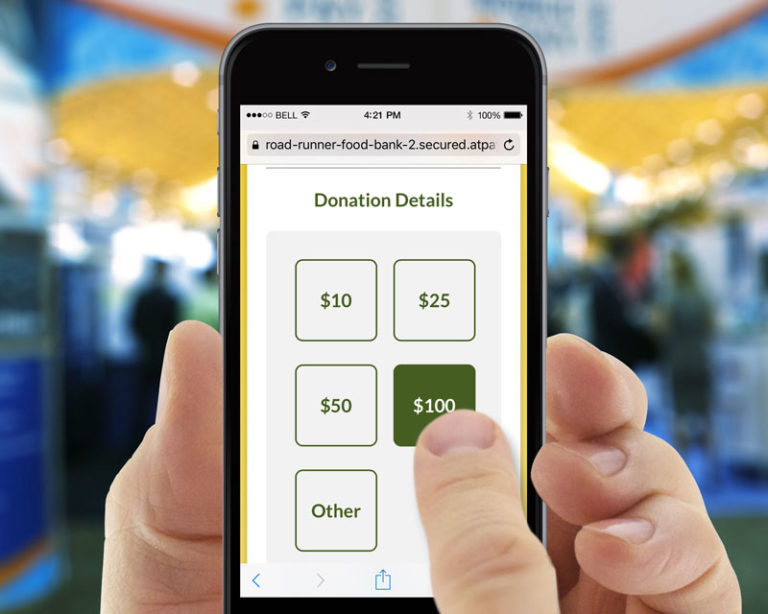 A hand holds up a smartphone displaying an online donation page as it selects one of the donation amounts with its thumb. 
