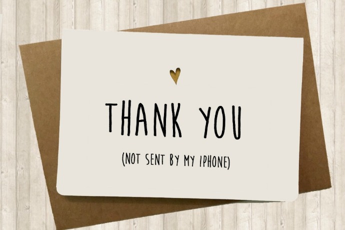 A card sitting on top of a brown envelope has “Thank you (not sent by my iPhone)” written by hand in black ink across the front. 