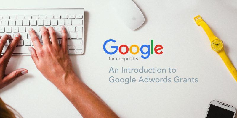 Hands type on a keyboard next to the Google logo and words introducing the AdWords Grants program.