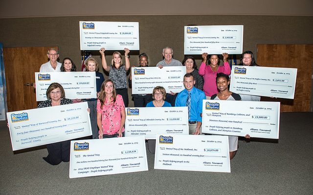 A group of nonprofit representatives pose with oversized grant checks.