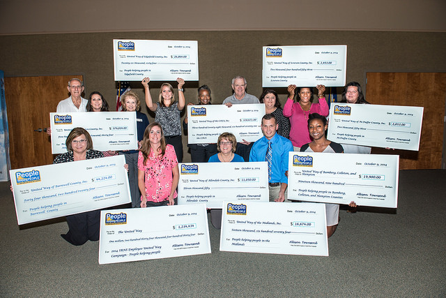 A group of nonprofit representatives pose with oversized grant checks.